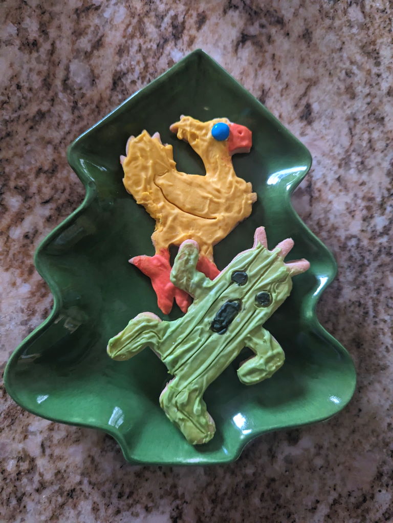 A Cactuar sugar cookie and a Chocobo sugar cookie on a plate shaped like a Christmas tree.