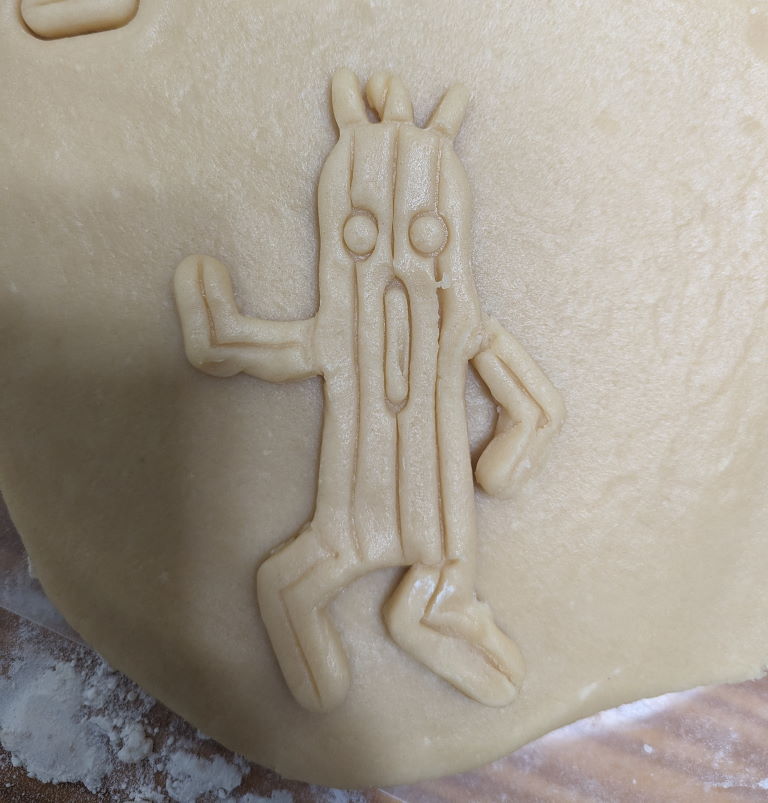 A Cactuar sugar cookie, fresh out of the cookie cutter but slightly stretched out. It looks like it's being tortured and in pain.