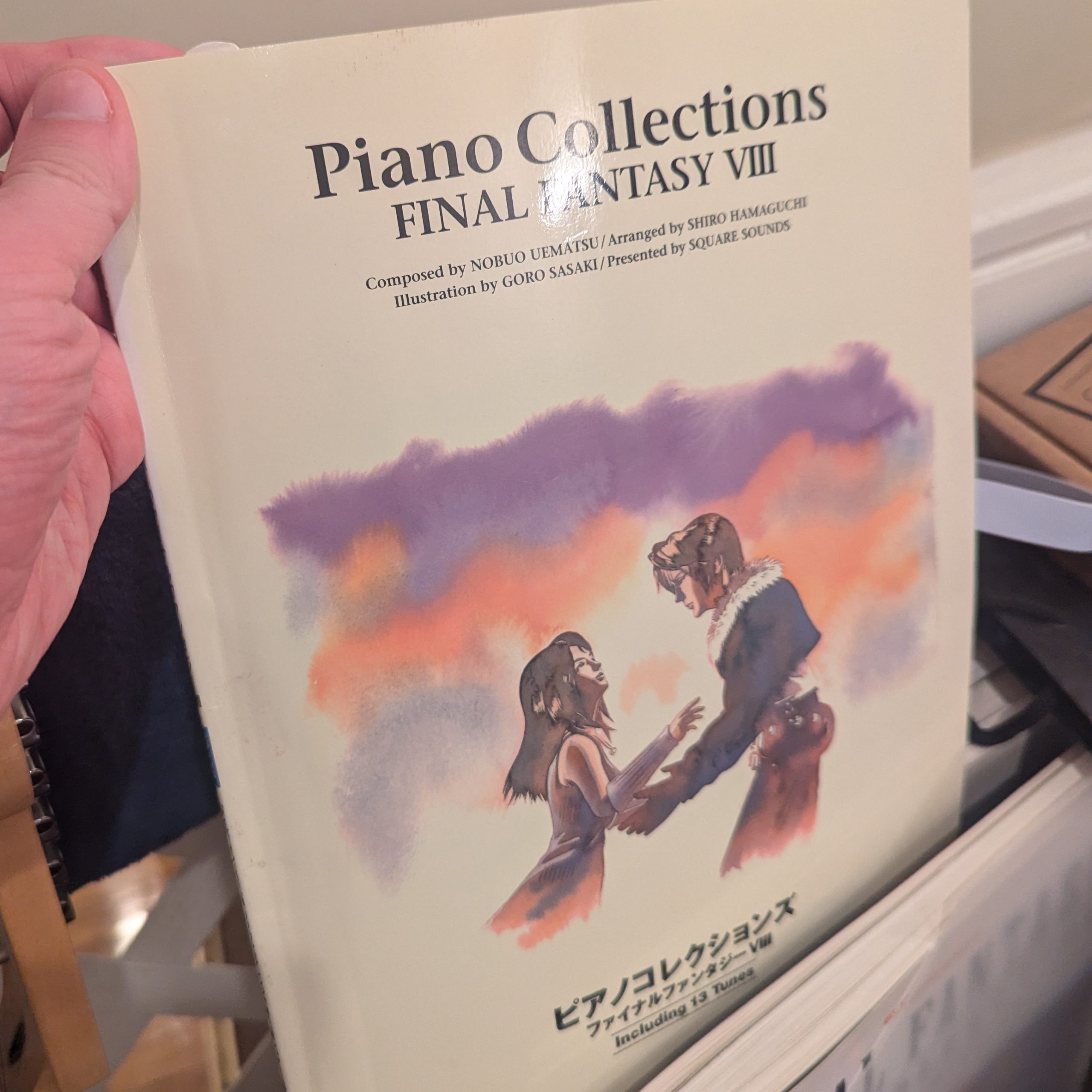 Holding a copy of the Piano Collections: Final Fantasy VIII sheet music book.