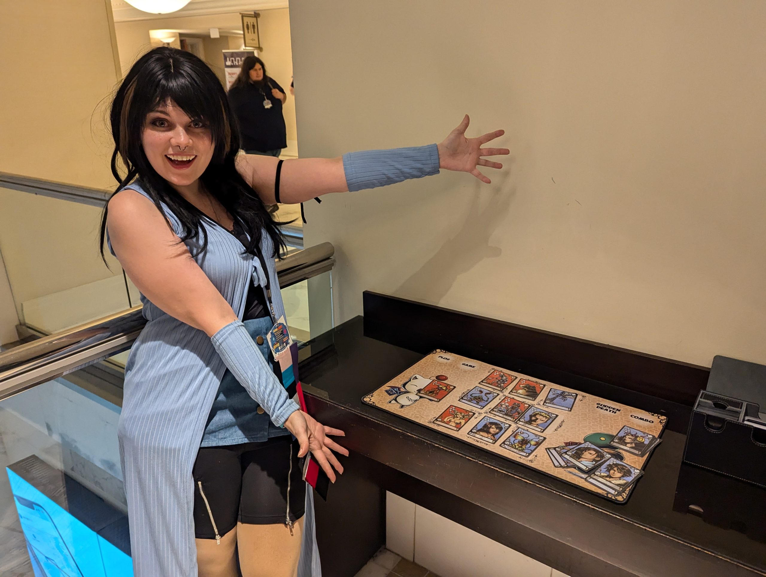 A Rinoa cosplayer posing next to a Triple Triad board.