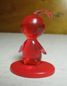 A tiny PuPu figurine made of transparent red plastic.