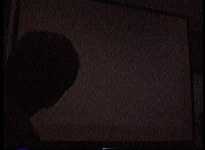 A blank projector screen in the dark, partially blocked by the silhouette of someone trying to figure out what the hell is going on.